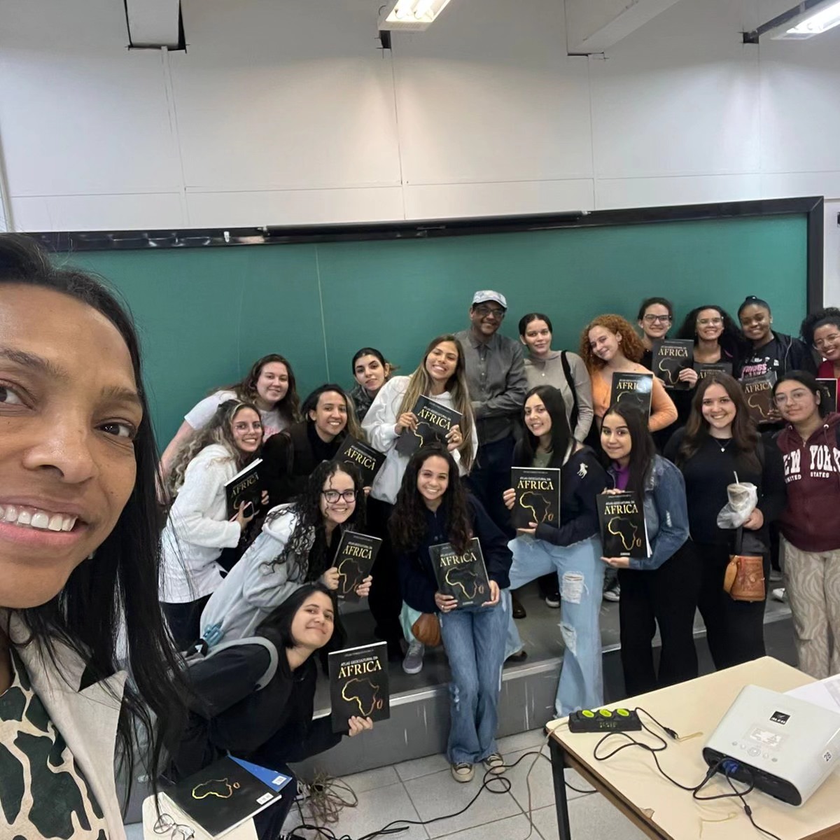 Grupo de estudantes segurando livros da Editora Eiros em uma palestra sobre cultura afro-brasileira.